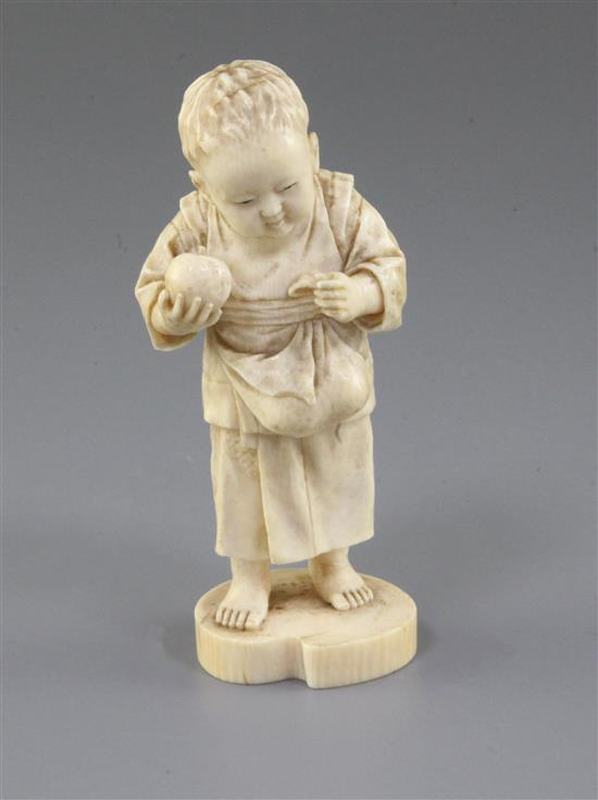 A Japanese ivory okimono of a boy holding a fruit, Tokyo School, Meiji period, 11.5cm